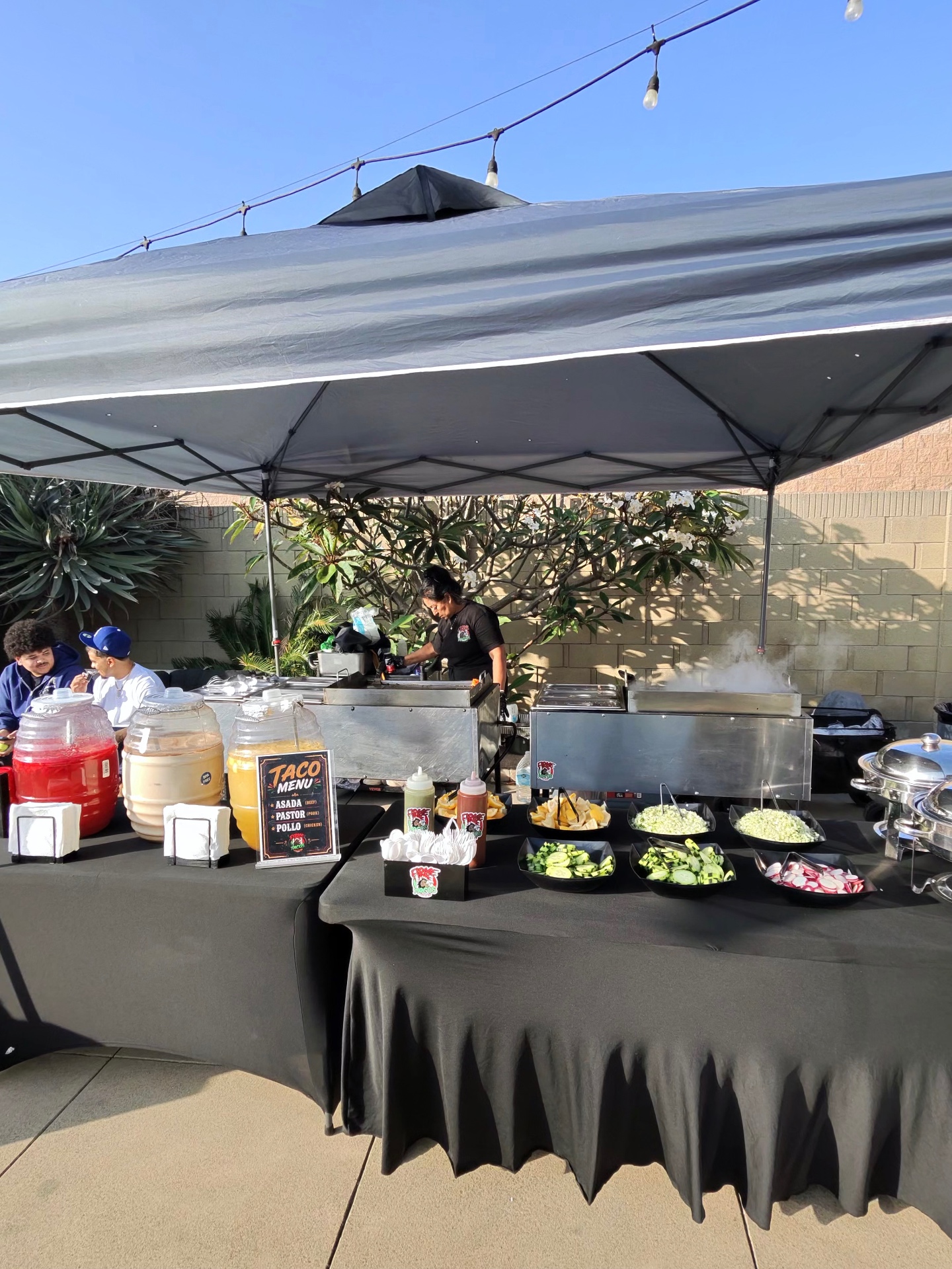 Firme Tacos Estilo Jalisco taco setup with plancha, salsas and toppings at an outdoor event